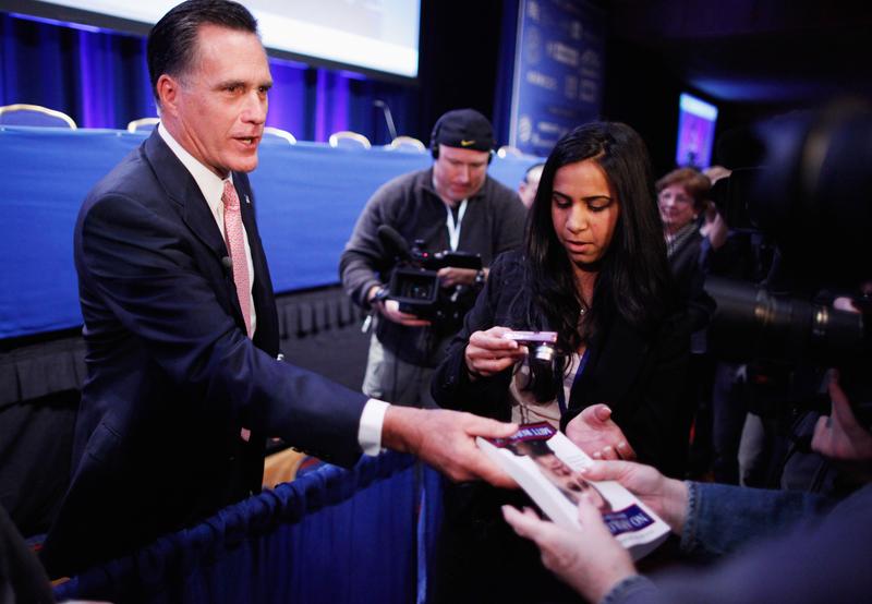 Former Massachusetts Governor Mitt Romney gives away paperback copies of his book, 'No Apologies,' after addressing the Conservative Political Action Conference in February 2011.